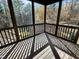 Enclosed screened porch with wooden flooring, offering a serene view of the surrounding nature at 10004 Liana Ln, Raleigh, NC 27613