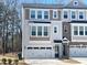 Charming townhome with a two-car garage and stylish exterior finishes on a sunny day at 10018 Secluded Garden Drive Rd # 187, Apex, NC 27523