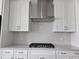 Modern kitchen boasts a gas stovetop, stainless vent hood, grey backsplash and white cabinets at 10018 Secluded Garden Drive Rd # 187, Apex, NC 27523