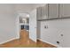 A functional laundry area with gray cabinets, hardwood floors, and easy access to the adjacent kitchen at 102 Switchback St, Knightdale, NC 27545