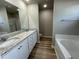 Elegant bathroom featuring double sinks, granite countertops, modern fixtures, and a separate tub at 103 Oakfield Trace Dr, Four Oaks, NC 27524