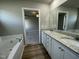Stylish bathroom showcasing a soaking tub, double vanity with granite counters, and access to the bedroom at 103 Oakfield Trace Dr, Four Oaks, NC 27524