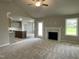 Open concept living area with fireplace, neutral carpet, and view into the kitchen at 103 Oakfield Trace Dr, Four Oaks, NC 27524