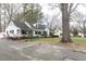 Mature trees surround a charming home with a brick walkway and mature landscaping at 105 John St, Louisburg, NC 27549