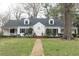 Charming two-story home with dormer windows, black shutters, brick walkway and mature landscaping at 105 John St, Louisburg, NC 27549