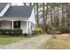 Charming side exterior showcasing black shutters, a brick pathway, and mature trees at 105 John St, Louisburg, NC 27549
