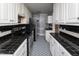 Well-appointed galley kitchen with white cabinetry, sleek black countertops, and vintage black appliances, offering a functional design at 105 John St, Louisburg, NC 27549