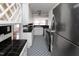 Galley kitchen featuring white cabinets, black countertops, and black and white patterned flooring, a blend of classic and modern at 105 John St, Louisburg, NC 27549