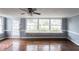 Inviting living room featuring hardwood floors, a ceiling fan, and ample natural light from large windows at 105 John St, Louisburg, NC 27549
