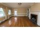 Warm living room with hardwood floors, a traditional fireplace, and large windows dressed with patterned curtains at 105 John St, Louisburg, NC 27549