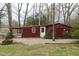 View of a rustic outbuilding with a quaint white door and a brick-lined fire pit, ideal for outdoor gatherings at 105 John St, Louisburg, NC 27549