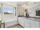 Bright bathroom featuring a double vanity with a gray countertop and a soaking tub beneath a large window at 108 Siebold St, Garner, NC 27529