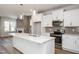 Modern kitchen with stainless steel appliances, white cabinets, and a large island with a sink at 1573 Piney Falls Dr, Wendell, NC 27591