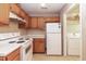 Well-lit kitchen with white appliances, wood cabinets, and convenient access to the laundry area at 3323 Nantuckett Ave, Durham, NC 27703