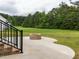 Backyard patio with brick fire pit and view of large grassy area bordered by mature trees at 4017 Mebane Oaks Rd, Mebane, NC 27302