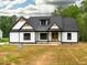 Charming home featuring a white exterior, dark roof accents, beautiful wooden front doors, and a well-kept lawn at 4017 Mebane Oaks Rd, Mebane, NC 27302