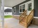 Covered outdoor living space with wooden steps and white pillars creates a inviting outdoor retreat at 4037 Mebane Oaks Rd, Mebane, NC 27302