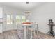 Bright dining area with modern light fixture, white table, and access to the backyard at 4037 Mebane Oaks Rd, Mebane, NC 27302