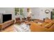 Bright living room featuring hardwood floors, a stylish leather sofa, and a view of the front yard at 424 S Greensboro St, Carrboro, NC 27510