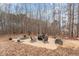 Cozy brick fire pit area featuring chairs, bench, and planters in a natural wooded backyard setting at 580 Long View Dr, Youngsville, NC 27596