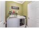 Laundry room with appliances, storage shelf and olive green walls at 580 Long View Dr, Youngsville, NC 27596