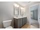Bathroom showcasing double vanity with gray cabinets and an open doorway to the bedroom at 6233 Pesta Ct, Raleigh, NC 27612