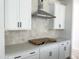 Kitchen detail featuring white cabinets, stone countertops, tile backsplash and stainless vent hood at 704 Compeer Way # 28, Rolesville, NC 27571