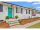 Inviting front porch featuring a vibrant turquoise door, black shutters, brick steps, and manicured landscaping at 928 Hanford Rd, Graham, NC 27253