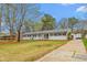 Charming single-story home with black shutters, a well-maintained lawn, a long driveway, and an inviting turquoise front door at 928 Hanford Rd, Graham, NC 27253