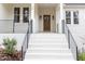Inviting front porch featuring white brick stairs, black railings and a charming stained wood door at 100 High Ridge Ln, Pittsboro, NC 27312