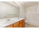 Bathroom featuring double sinks, wood cabinets, an oversized mirror, and neutral tile at 1009 Limeberry Ct, Clayton, NC 27520