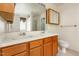Bathroom featuring double sinks, wood cabinets, an oversized mirror, and neutral tile at 1009 Limeberry Ct, Clayton, NC 27520