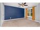 Bedroom with blue accent wall, neutral carpet, ceiling fan, and large window with natural light at 101 Lager Ln, Garner, NC 27529