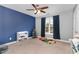 Bright bedroom with gray carpet, a blue accent wall, and a ceiling fan with light at 101 Lager Ln, Garner, NC 27529