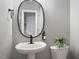 Chic half bath with a pedestal sink, oval mirror, and a decorative plant, offering a stylish touch at 101 Redfoot Run Rd, Chapel Hill, NC 27516