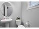 A quaint powder room features a pedestal sink, a round mirror, neutral paint, and modern fixtures at 109 Belle Plain Dr, Morrisville, NC 27560