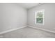 Bright bedroom with plush carpet and a window overlooking the tree lined backyard at 109 Belle Plain Dr, Morrisville, NC 27560