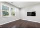 This room features a wall mounted television, dark wood floors, and two large windows letting in natural light at 109 Belle Plain Dr, Morrisville, NC 27560