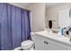 Well-lit bathroom with a shower, toilet, vanity with sink, and a blue shower curtain at 147 Everwood Dr, Four Oaks, NC 27524