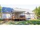 Home's rear view showcases a covered porch with a ceiling fan and wooden railing at 1516 Bradsher Dr, Stem, NC 27581