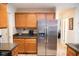 Well-lit kitchen features stainless steel refrigerator and oak cabinetry with granite countertops at 1516 Bradsher Dr, Stem, NC 27581
