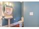 Chic powder room with a pedestal sink, decorative mirror, and stylish blue walls at 201 Finsbury St # 201, Durham, NC 27703