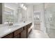 Bathroom featuring dual sinks, dark wood cabinets, large mirror and glass shower at 2340 Beeblossom Pl, Fuquay Varina, NC 27526