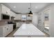 Bright kitchen with white cabinets, stainless steel appliances, large island and pendant lighting at 2340 Beeblossom Pl, Fuquay Varina, NC 27526