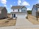 Charming two-story home featuring a two-car garage, landscaped yard, and a welcoming blue front door at 25 Carlton Ln, Franklinton, NC 27525