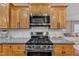 Kitchen featuring a stainless steel stove with a microwave above, wood cabinets, and tile backsplash at 250 Spring View Ln, Pittsboro, NC 27312