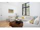 Bright living room showcasing a large sectional sofa, hardwood floors, and a large black trim window at 336 Timberline Dr, Pittsboro, NC 27312