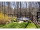 A trampoline in a wooded backyard next to a fence with bright yellow flowers and lush green grass at 336 Timberline Dr, Pittsboro, NC 27312