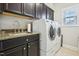 Well-lit laundry room with dark cabinets, granite countertop, stainless steel sink, and modern washer and dryer at 3929 Glenlake Garden Dr, Raleigh, NC 27612