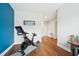Home office featuring a blue accent wall, leading to a hallway, hardwood floors and an exercise bike at 3929 Glenlake Garden Dr, Raleigh, NC 27612